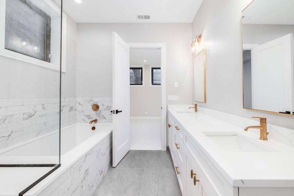 Modern bathroom in Chandler with a double vanity featuring light wood cabinets and quartz countertops with two vessel sinks and chrome faucets.