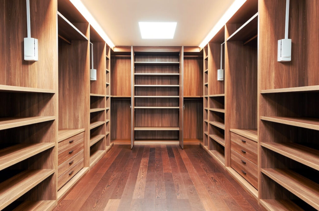 Walk-in closet in Phoenix with custom wood shelving, drawers, and hanging rods