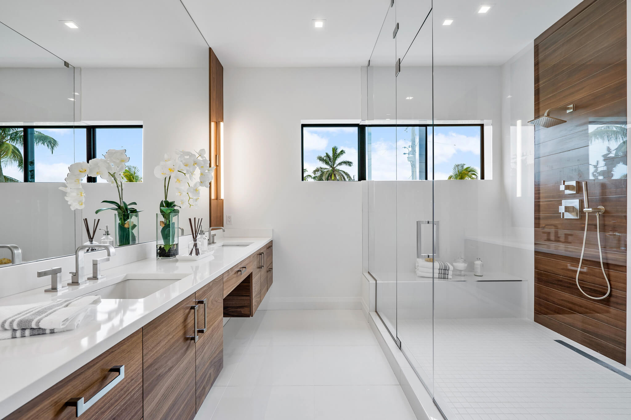 Bathroom vanity with light wood cabinets and geometric tile backsplash.