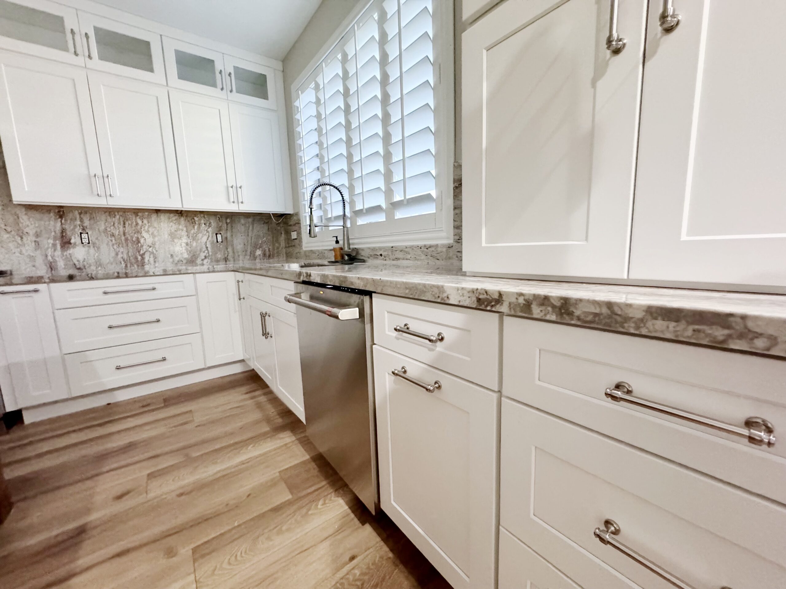 Chic kitchen corner showcasing alabaster cabinetry, marble backsplash, and hardwood flooring.