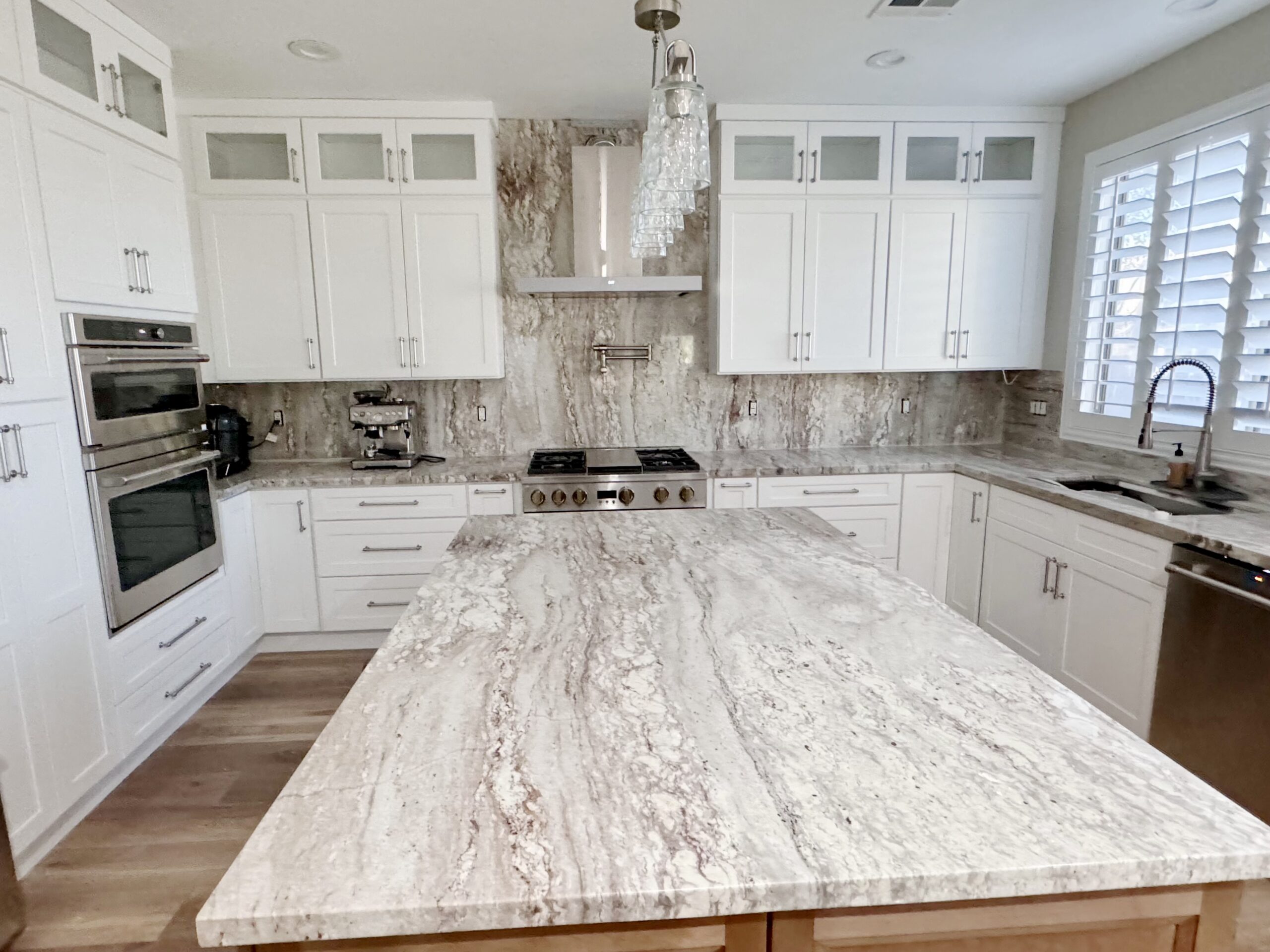 Modern kitchen with contrasting alabaster and walnut cabinetry, marble surfaces, and hardwood floors.