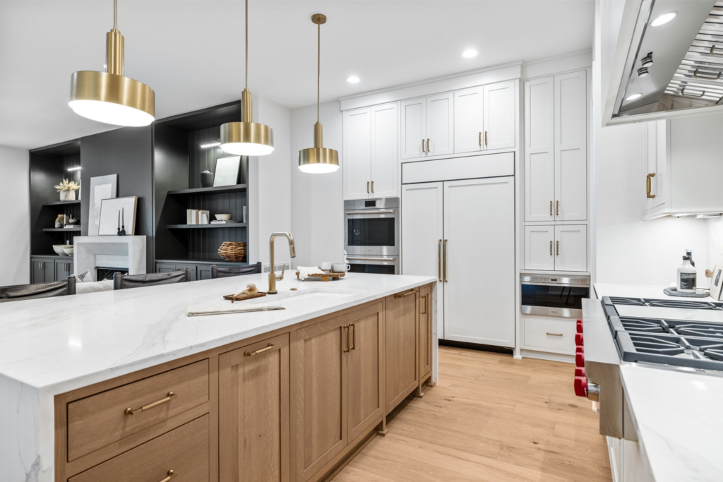 A modern kitchen with a large center island in Gilbert featuring white cabinets with chrome hardware and pendant lights.