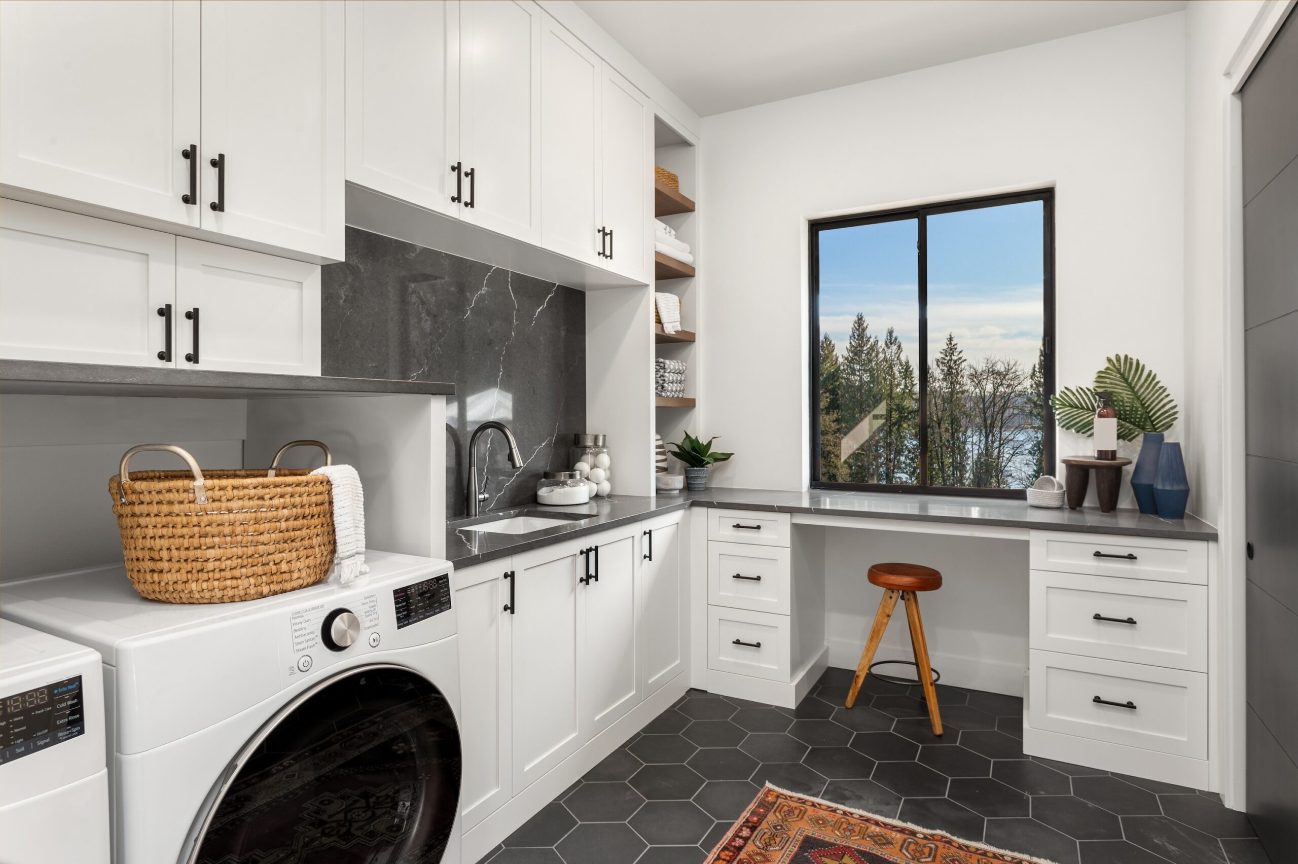 Well-organized laundry room in Chandler with custom cabinets, countertops, sink, drying rack, and stool.