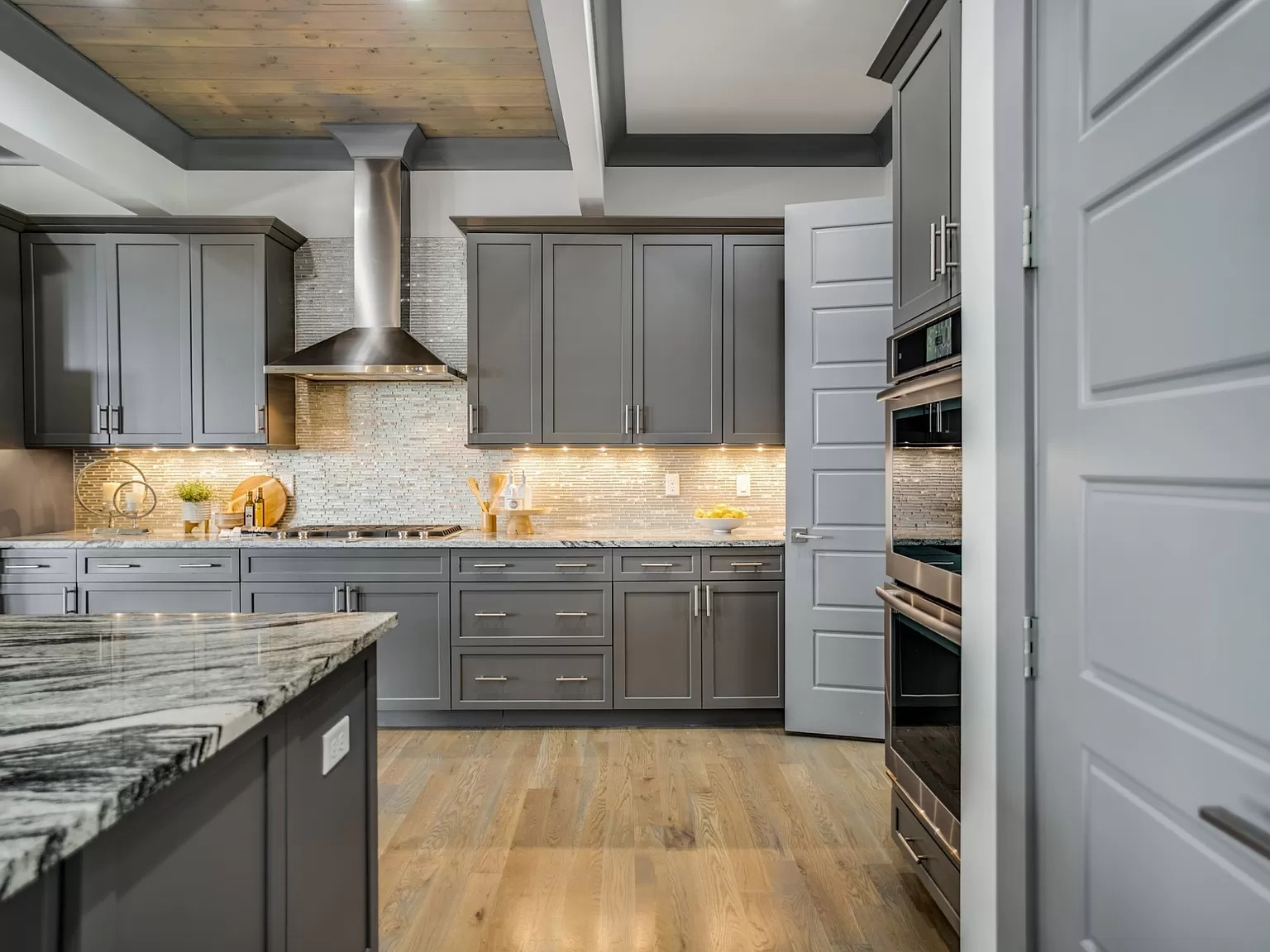 Modern kitchen with dark gray cabinets and wooden ceiling.