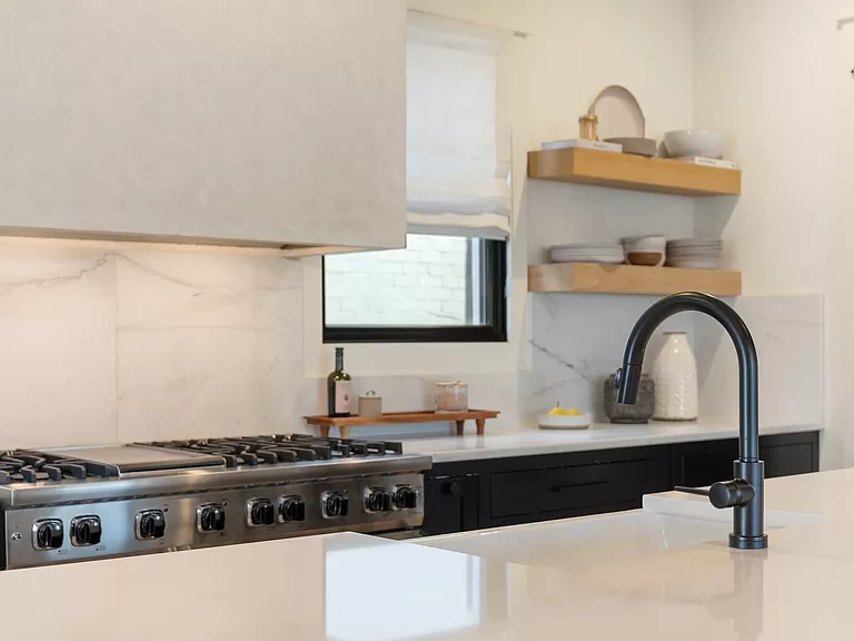 Sleek Kitchen Detailing with Black Cabinets and Marble Backsplash