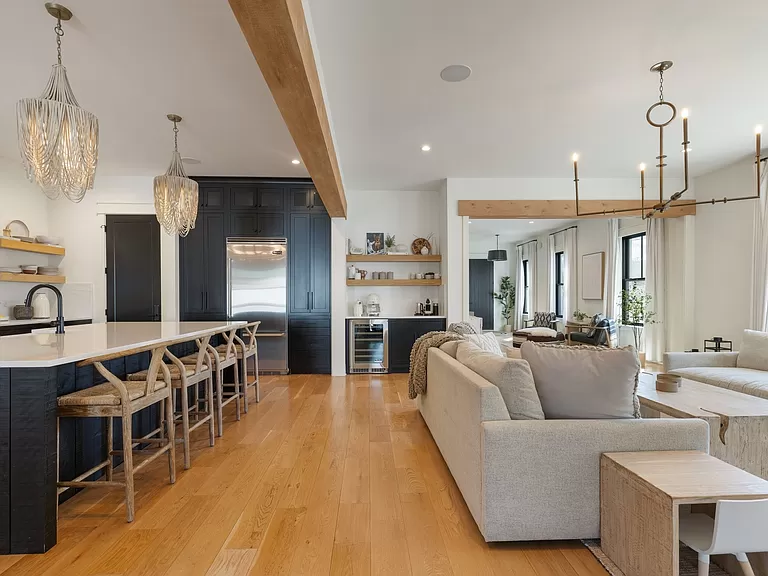 Luxurious open-plan kitchen with elegant chandeliers, navy cabinetry, and a comfortable living area.