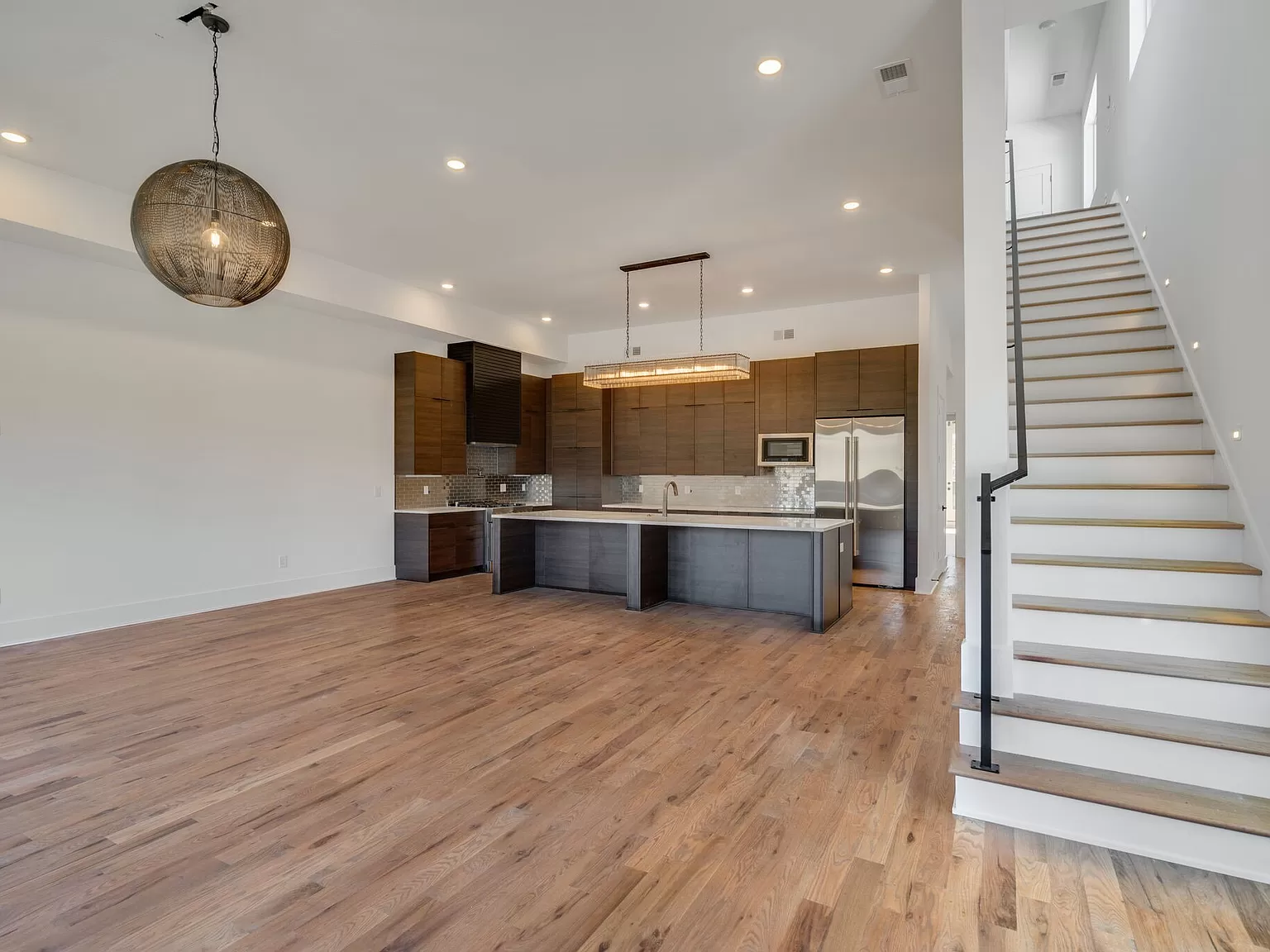 Spacious room with kitchen and staircase.